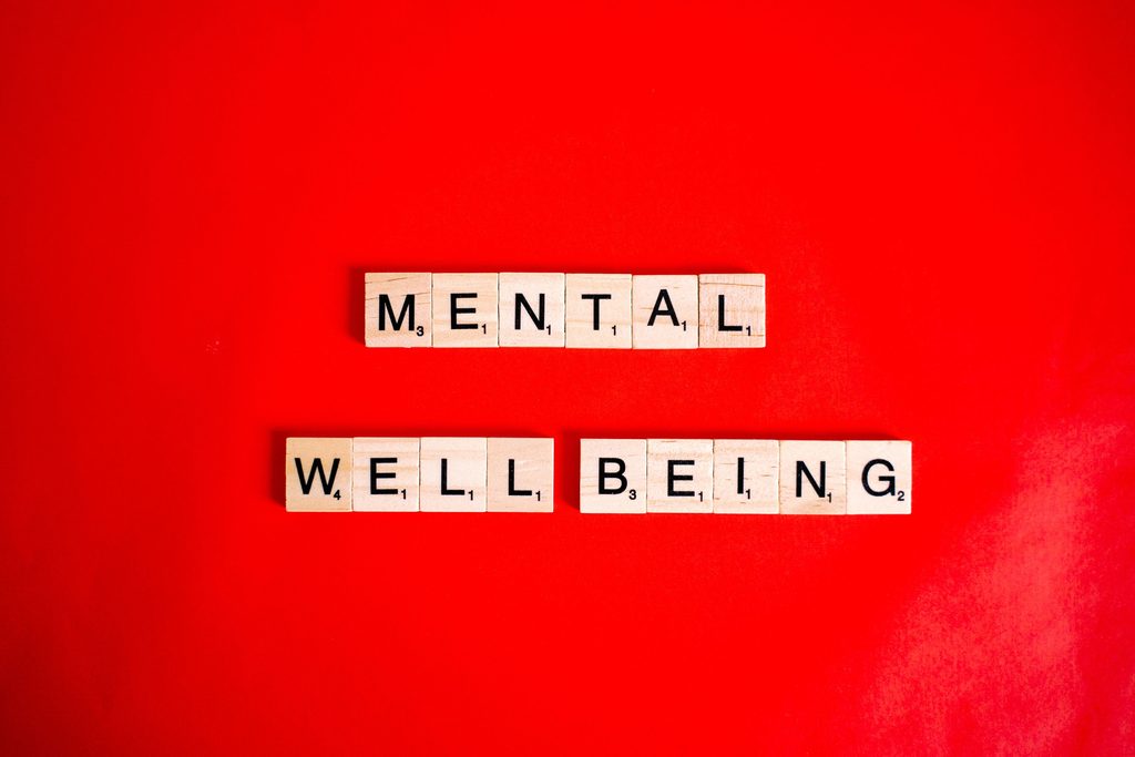 Wooden letter tiles spelling the word mental on a red background